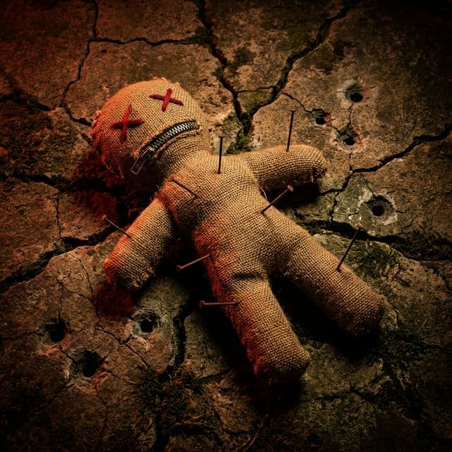 Voodoo doll on cracked stone — targeted but unbroken